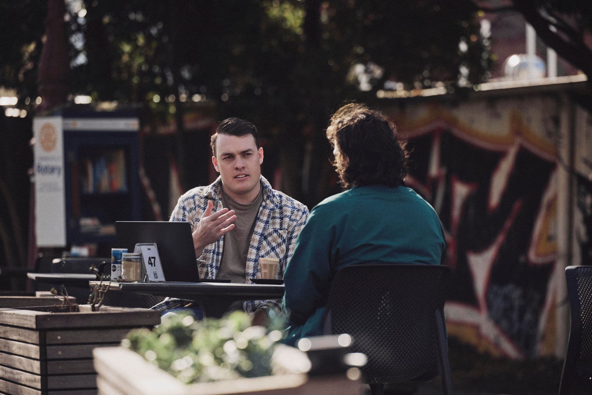 Jacob talking a client through figures on a laptop at an outdoor café table