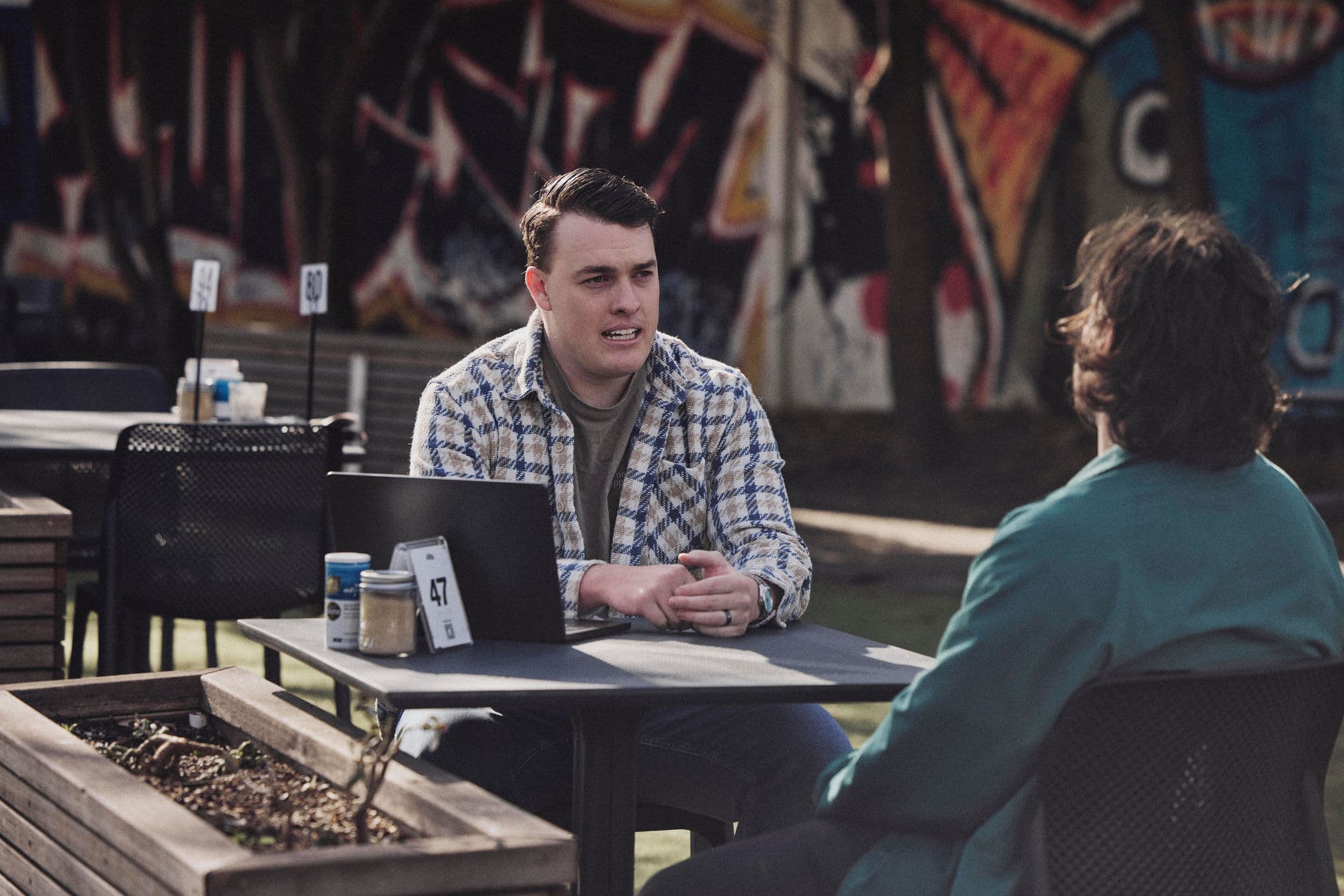 Jacob explaining something to a client across a café table, a laptop open between them